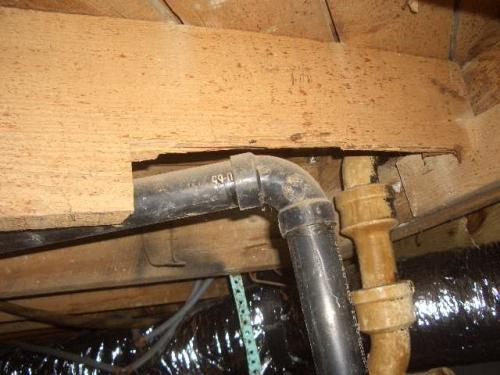 A drain line that has a negative slope and cut floor joist found on a Charlotte Home Inspection